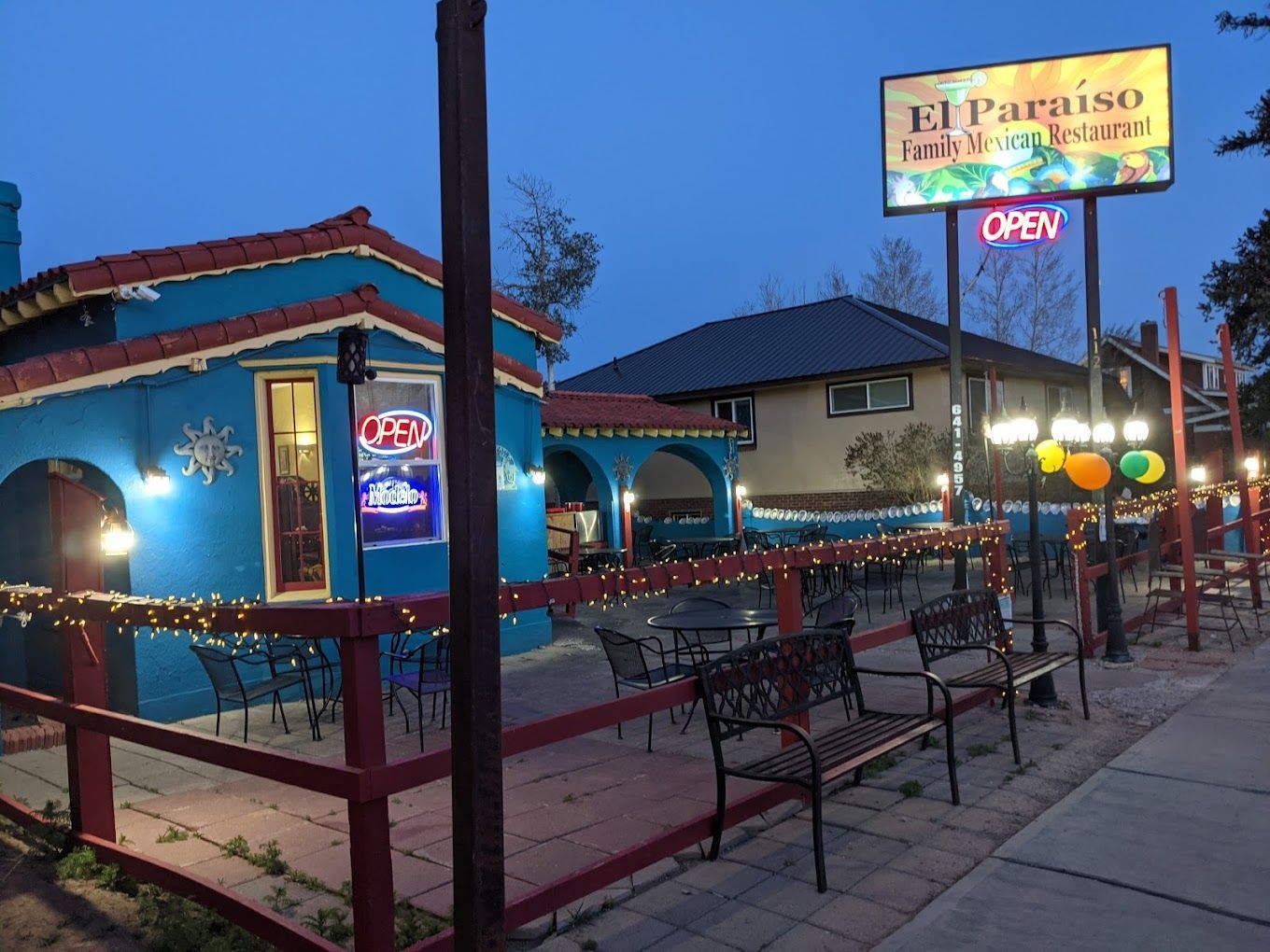 A restaurant called el paraiso is lit up at night