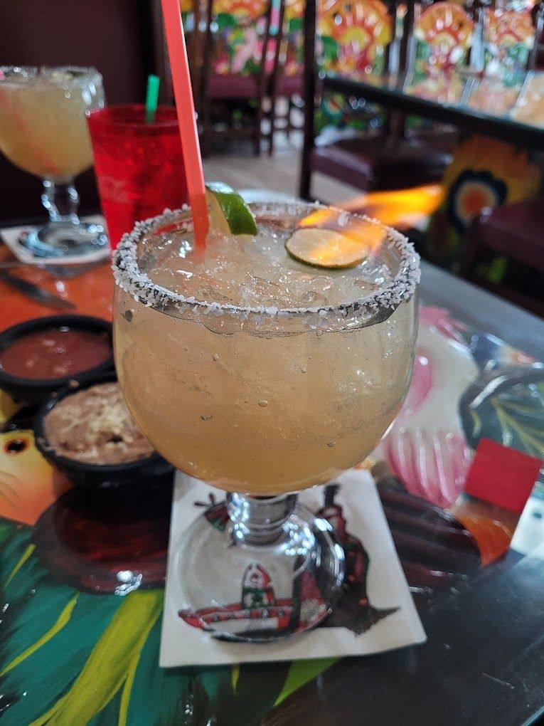A margarita is sitting on a coaster on a table.