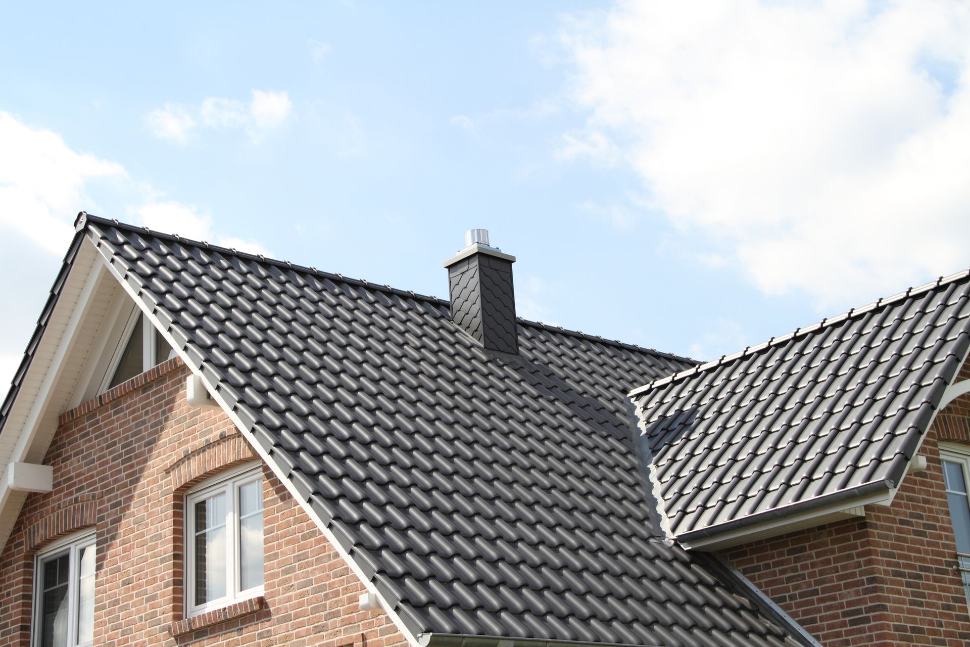 A brick house with a black roof and a chimney.