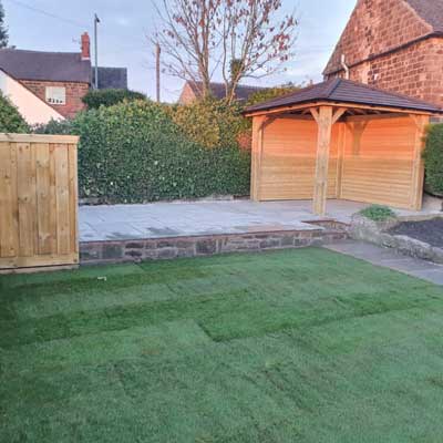 Astroturf lawn with a wooden structure in the corner and low brick walls around the outside