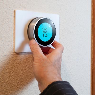 A person is adjusting a thermostat to 72 degrees
