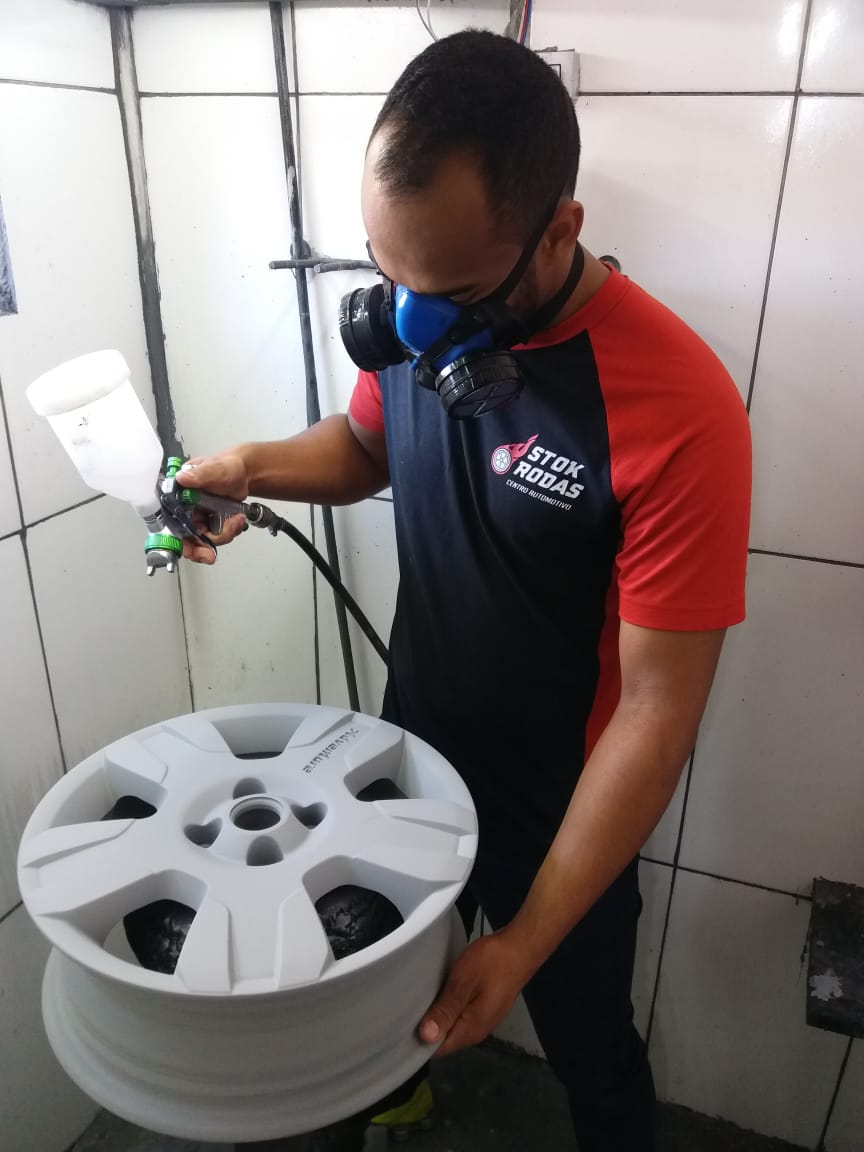Um homem usando uma máscara está borrifando tinta em uma roda