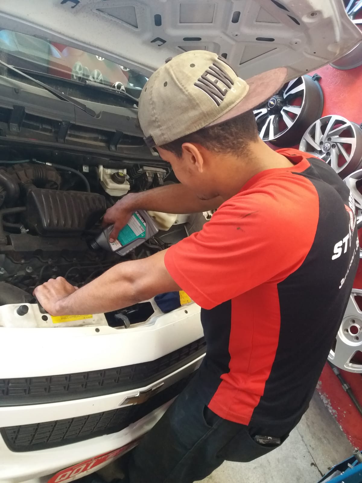 Um homem usando um chapéu está trabalhando sob o capô de um carro.