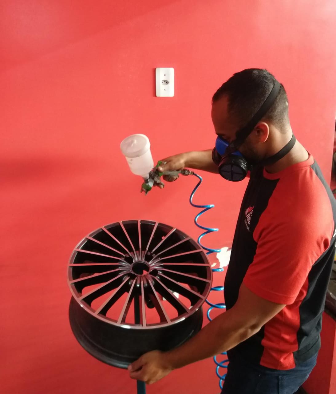 Um homem usando uma máscara está borrifando tinta em uma roda