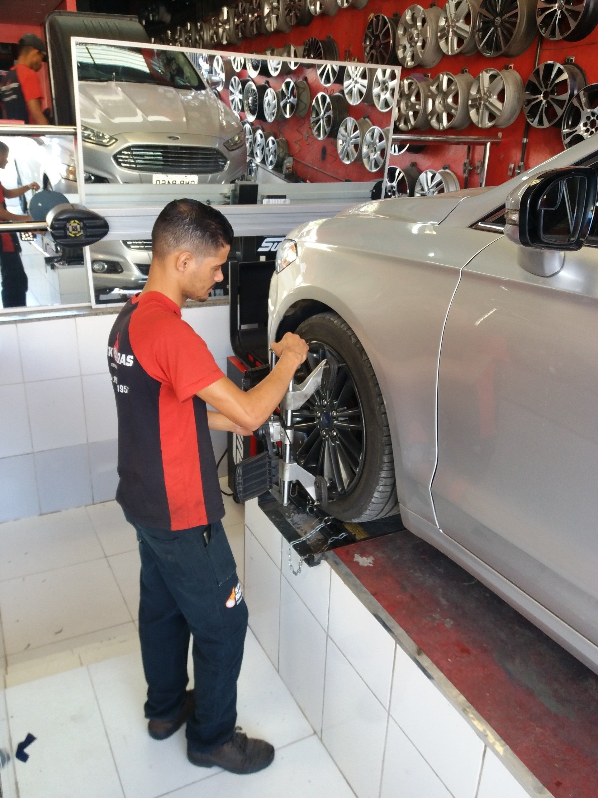 Um homem de camisa vermelha e preta está trabalhando em um carro