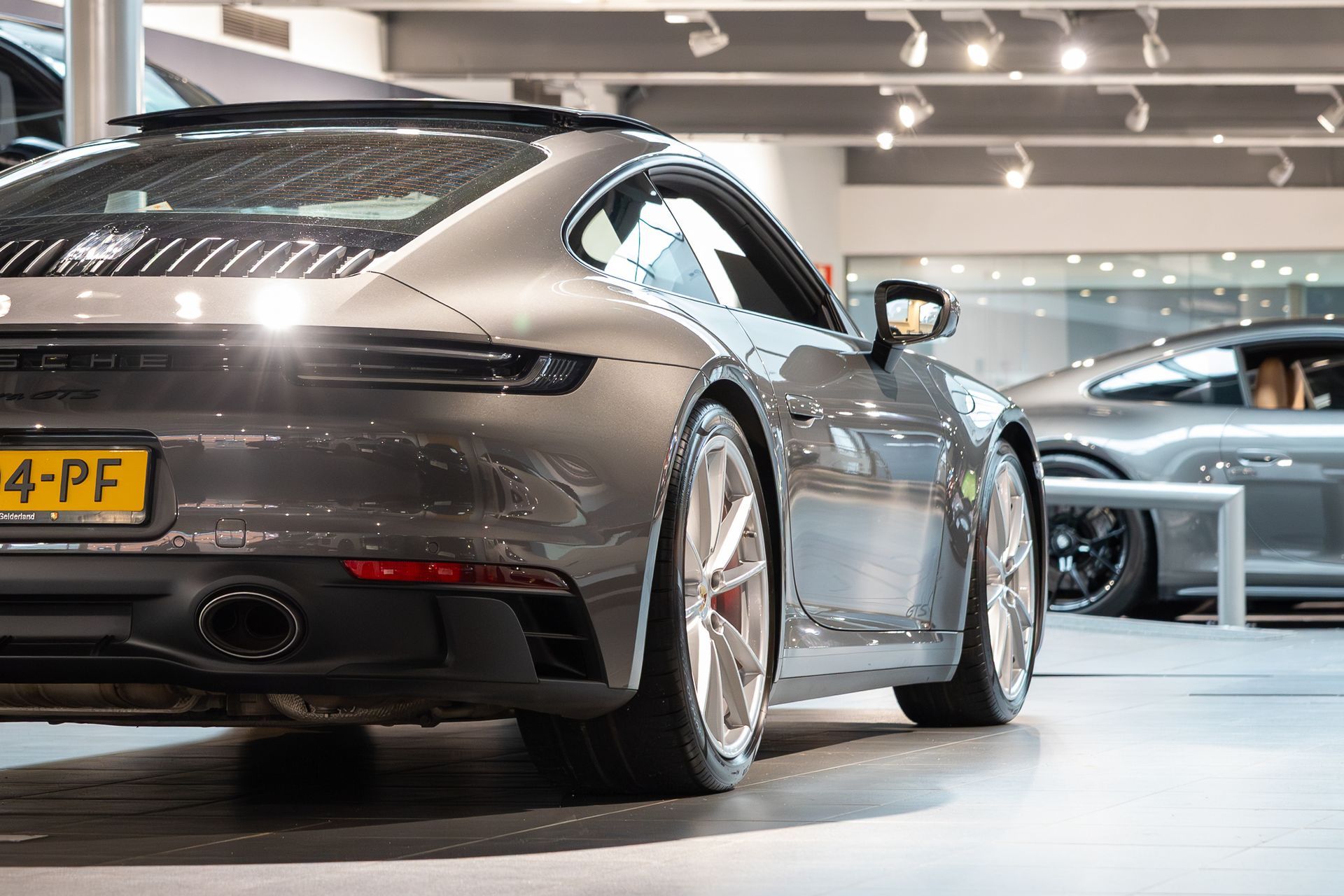 Grijze Porsche sportwagen geparkeerd in een showroom.