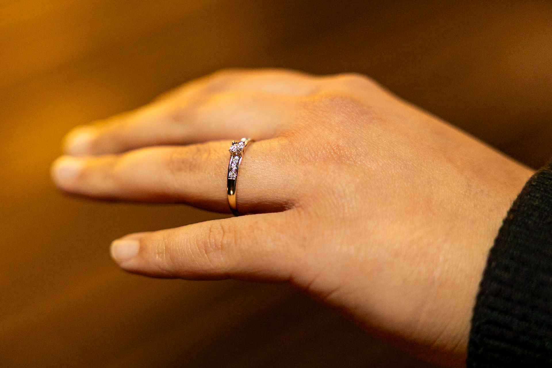 Hand met een gouden ring, mogelijk een verlovings- of trouwring. Bruine achtergrond.