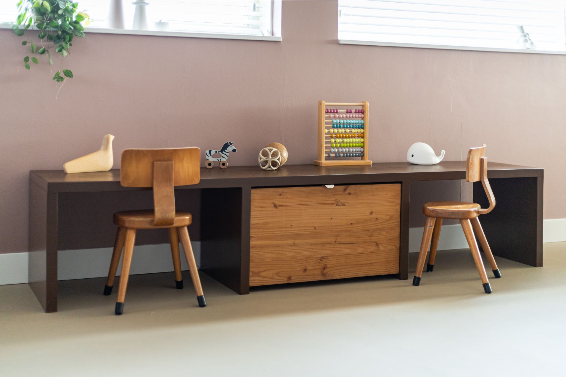 Houten bureau met twee kleine stoeltjes, telraam, speelgoed en ladeblok.