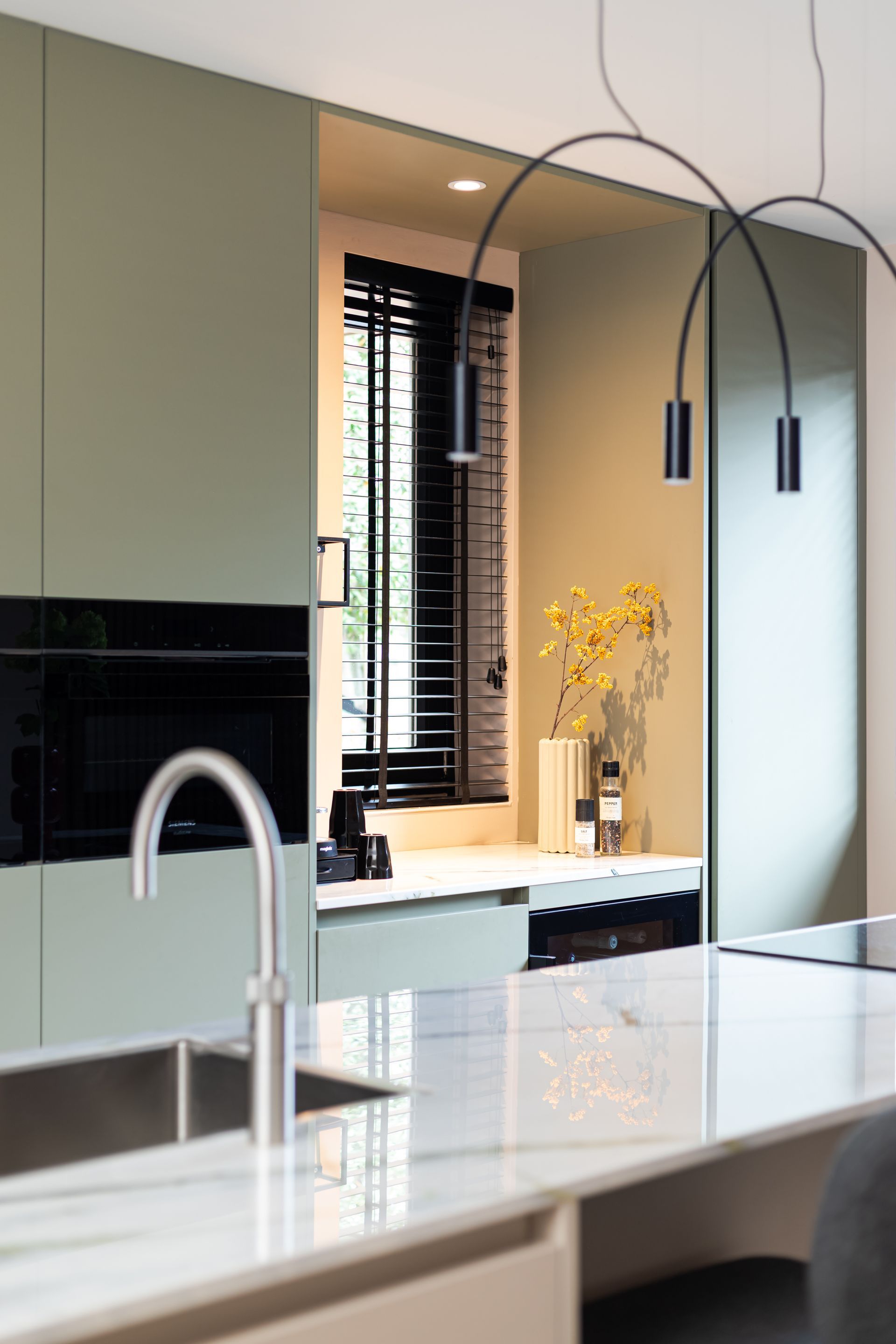 Trap met donkerblauwe leuning en hangende geometrische hanglampen, waarvan één met een rood pijlontwerp.