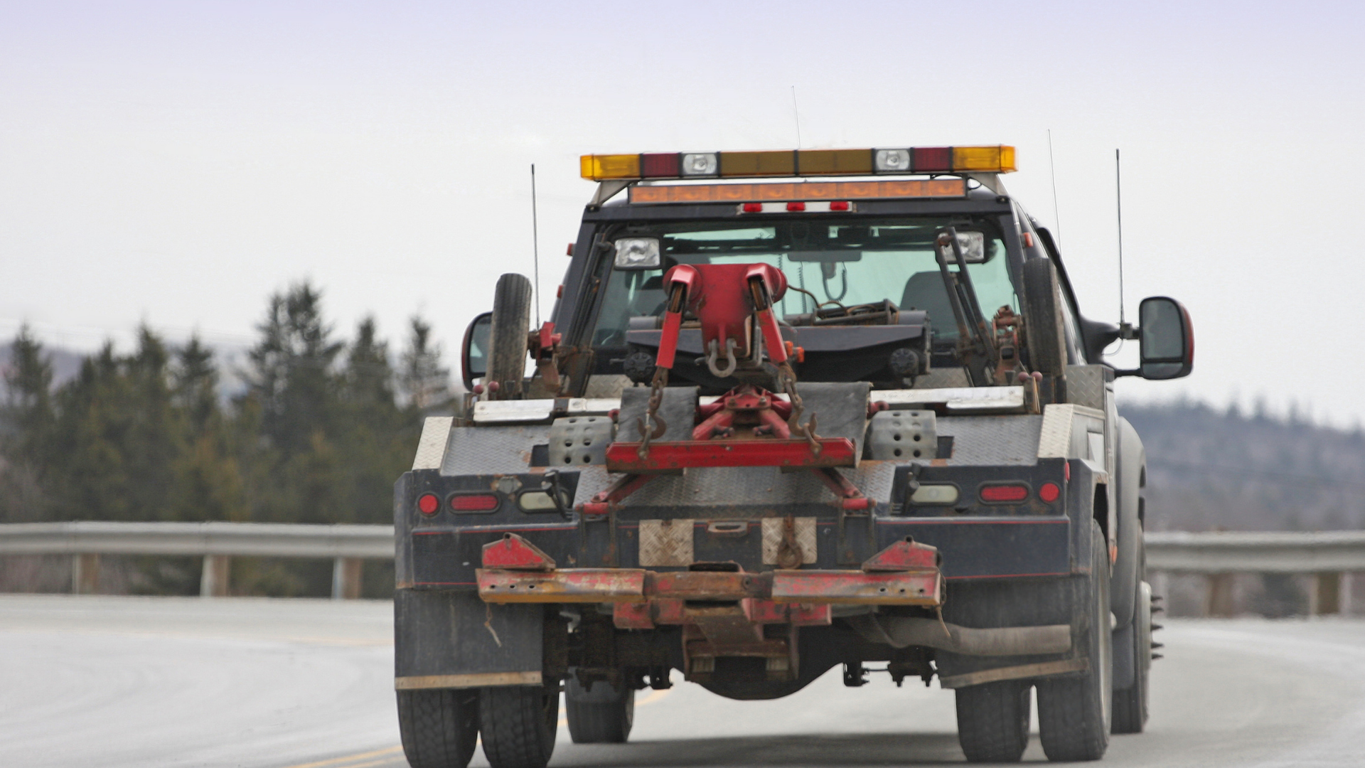 Tow truck with red and orange lights on the road.