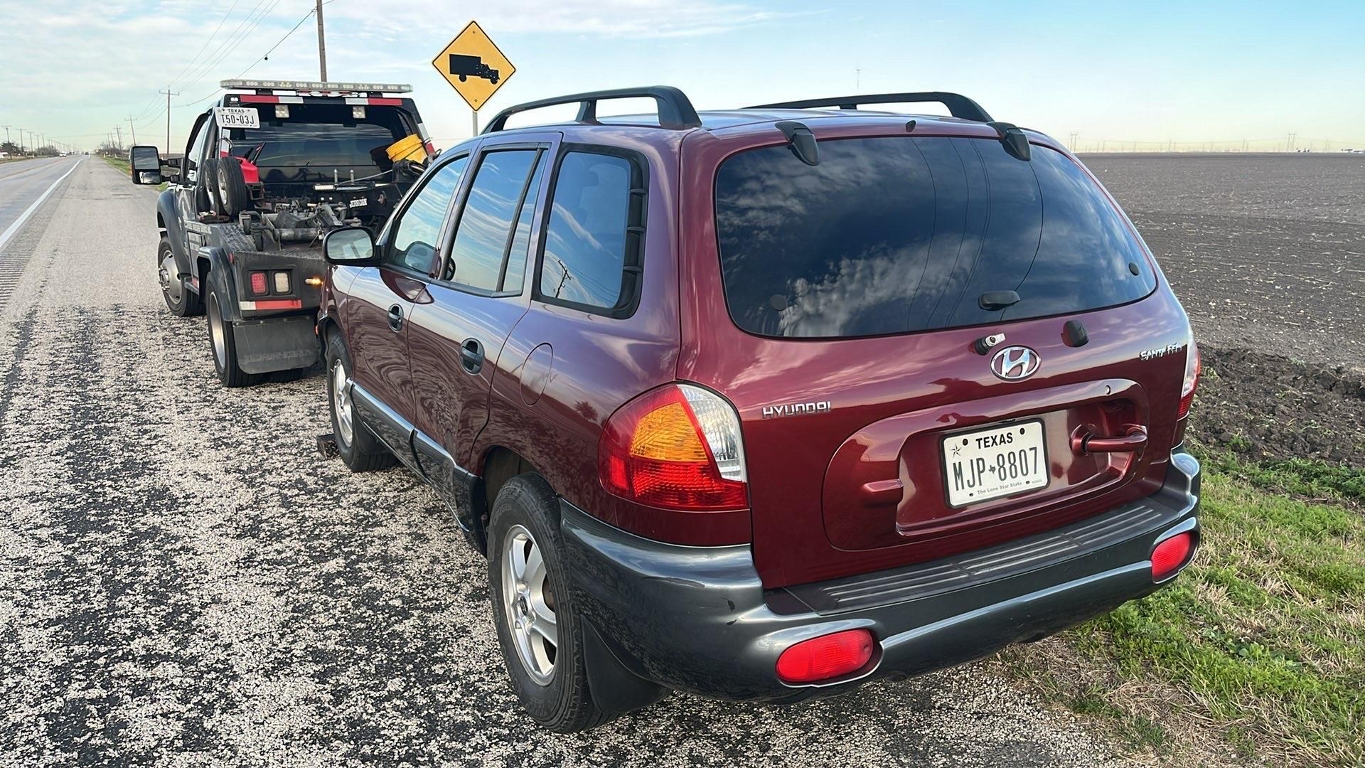 Red reflective warning triangle on road with person at a car.