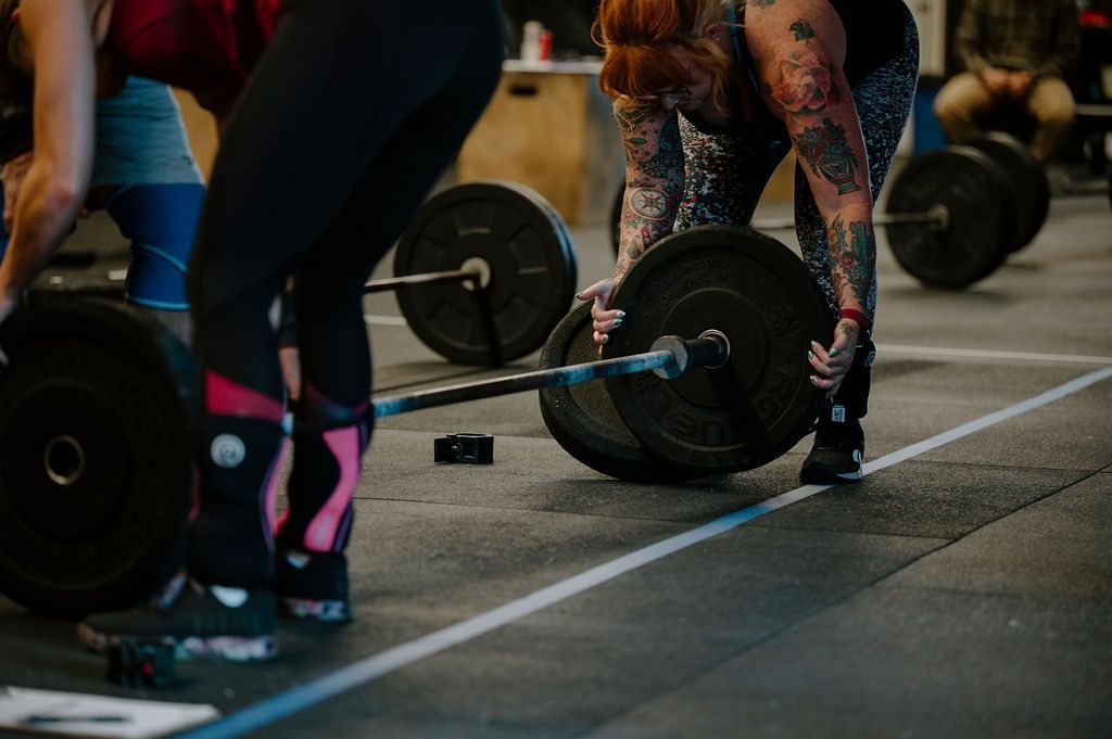 A woman is lifting a barbell in a gym.