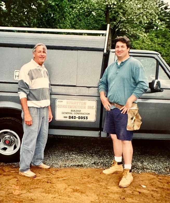 Two men standing in front of a van that says kingsford