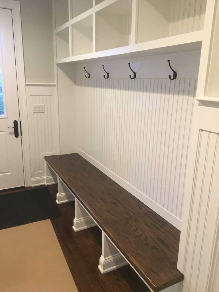 A hallway with a bench and hooks on the wall