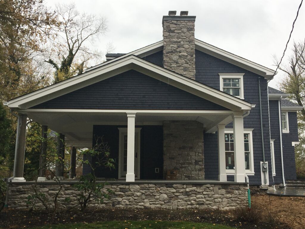 A blue house with a stone porch and a chimney