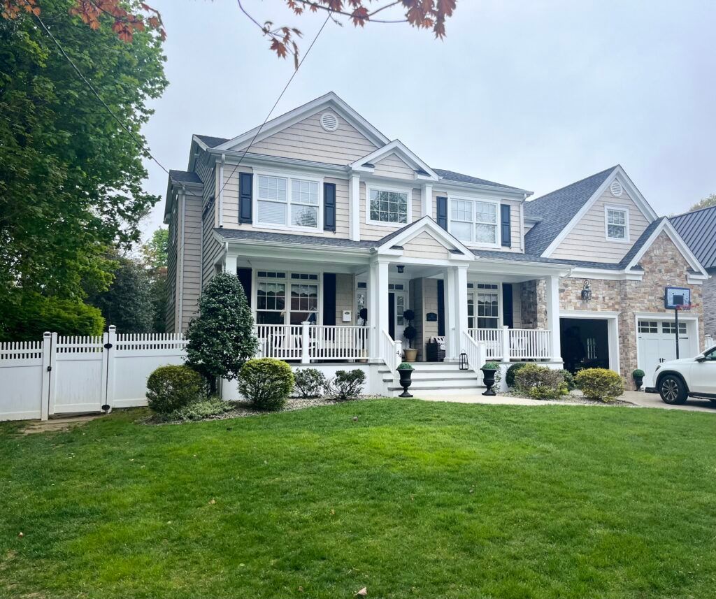 A large house with a white picket fence and a car parked in front of it.
