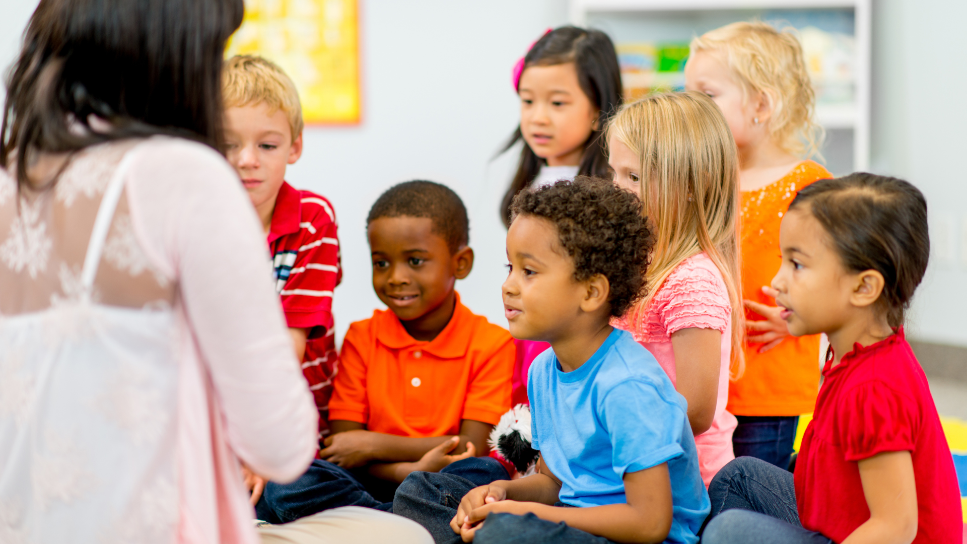 a group of children are sitting on the floor listening to a story .