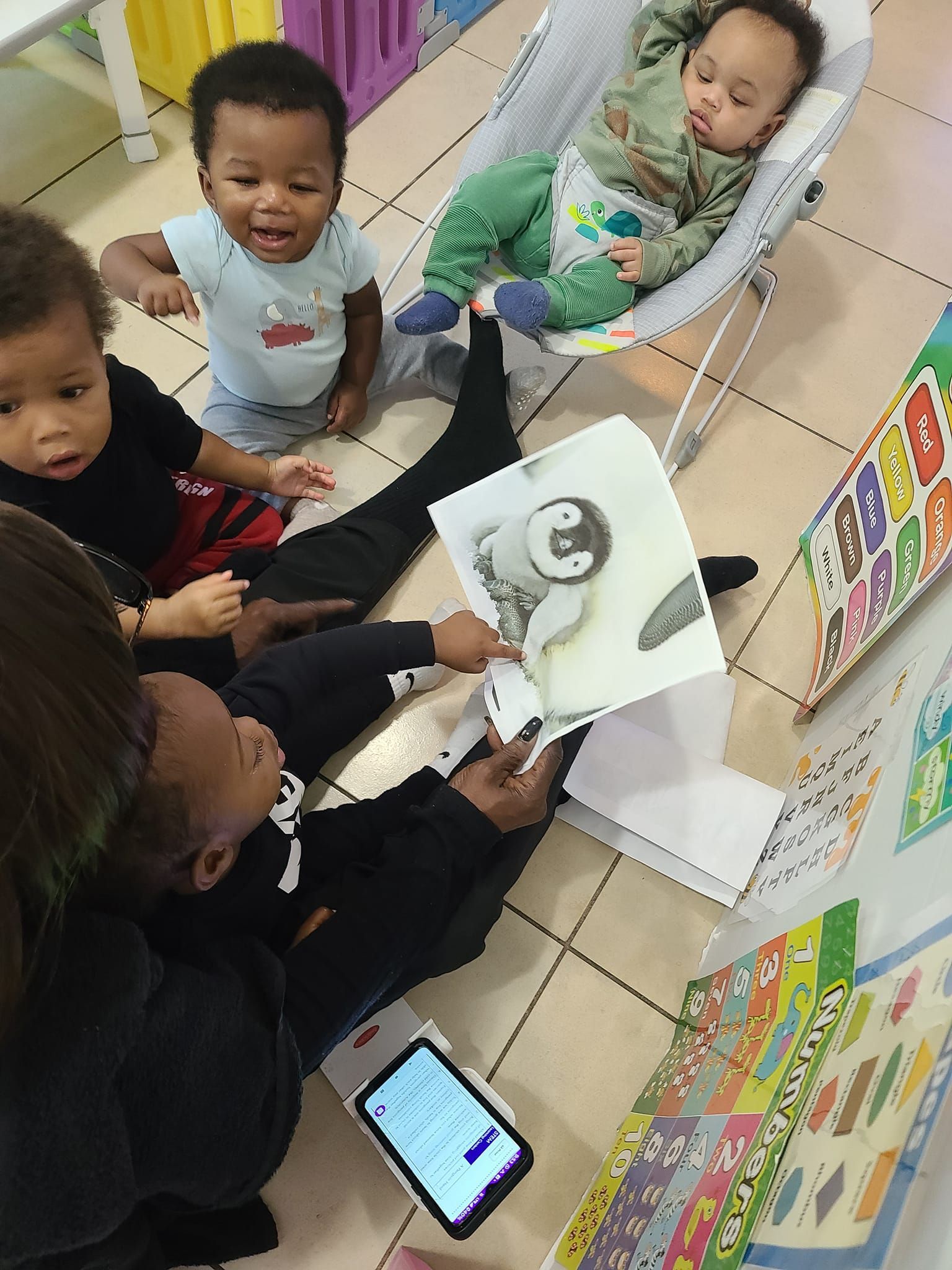 A group of babies are sitting on the floor reading a book.