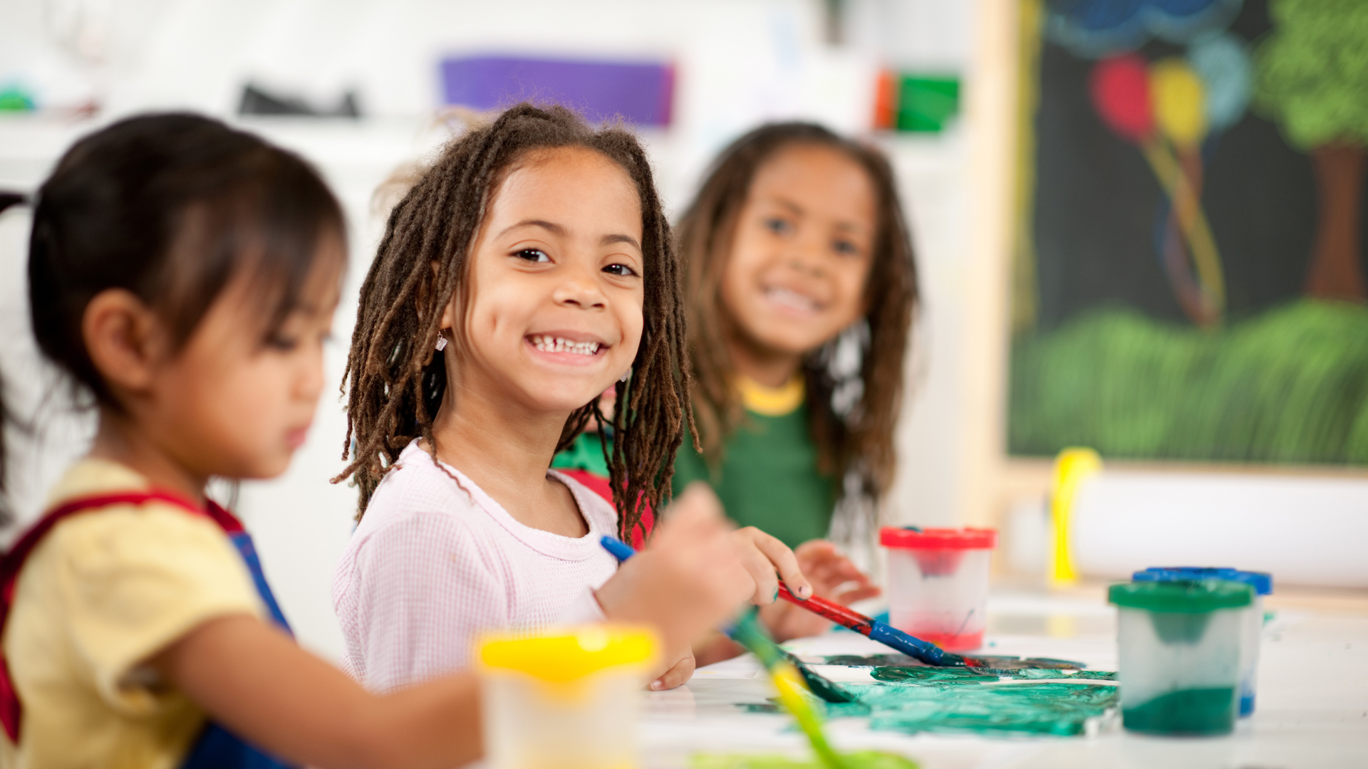 A group of young girls are sitting at a table painting.