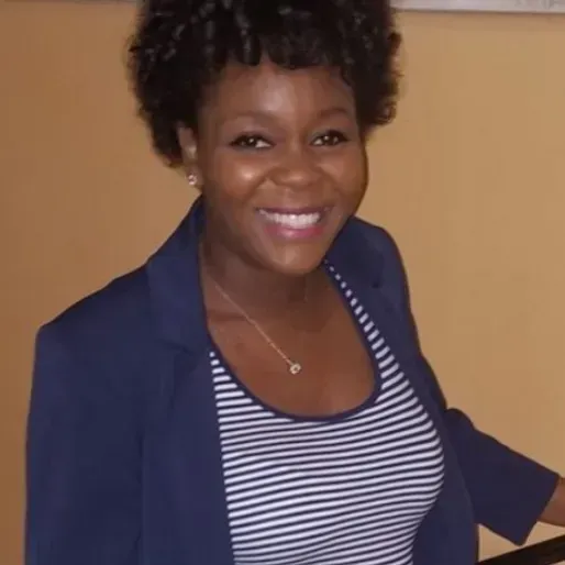 a woman wearing a striped shirt and a blue jacket smiles for the camera