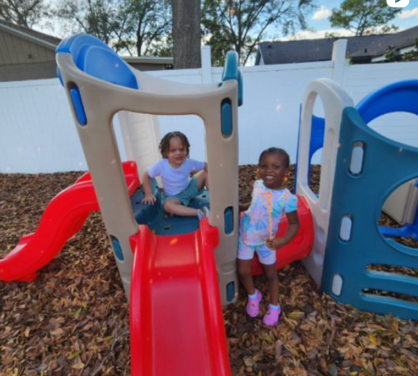 two children are playing on a slide in a playground