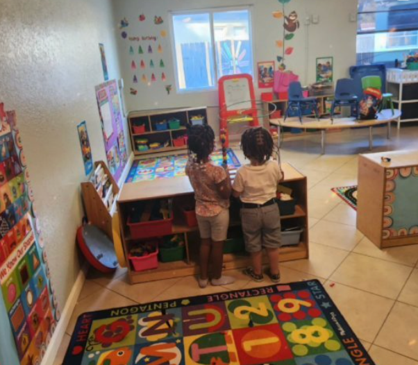 two children are standing in a room with a rug that has the alphabet on it