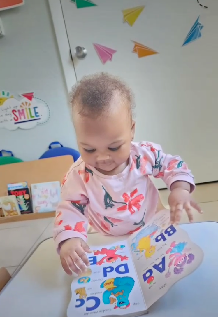a baby is sitting at a table reading a book