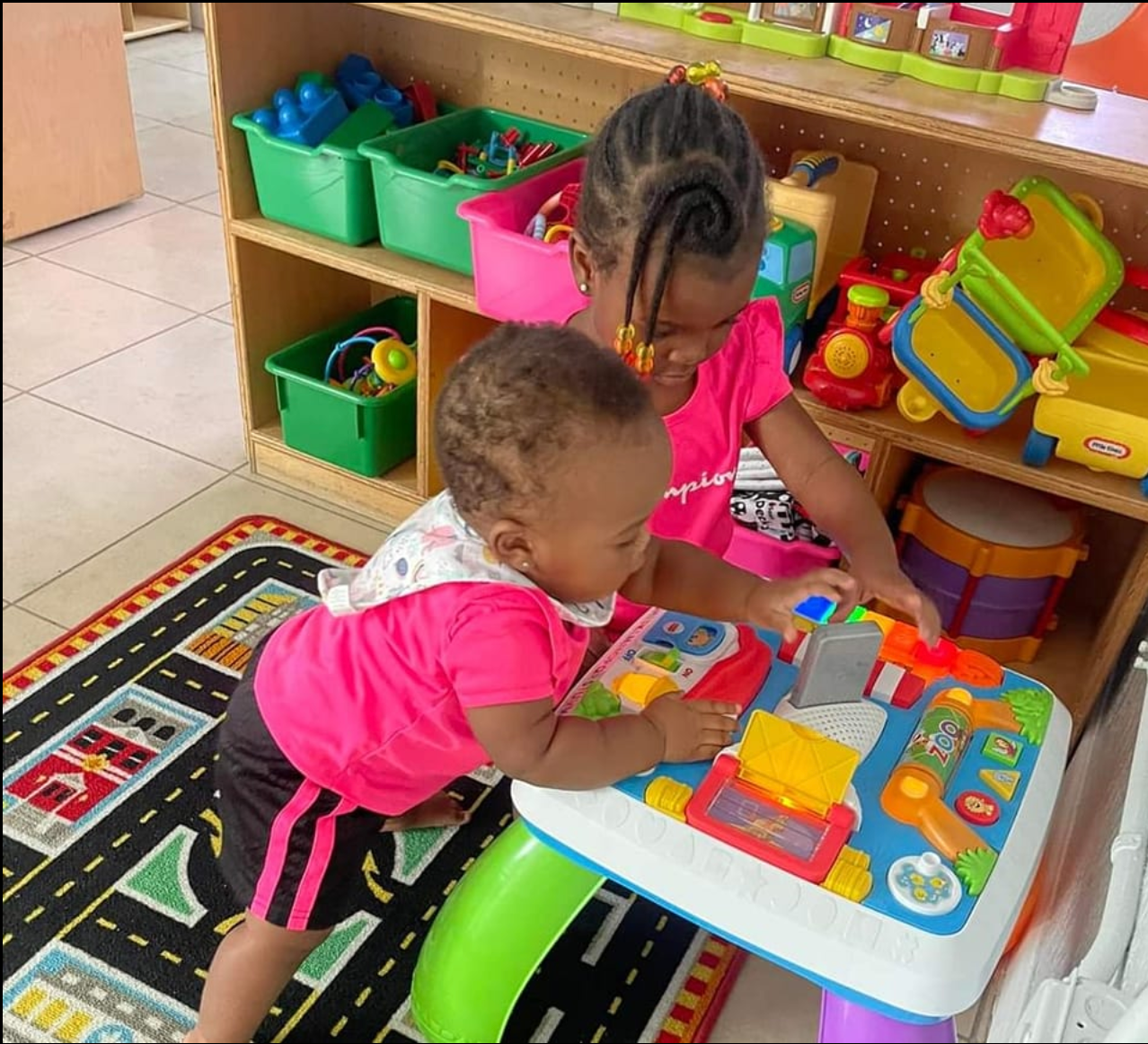 Two children are playing with a toy table in a play room