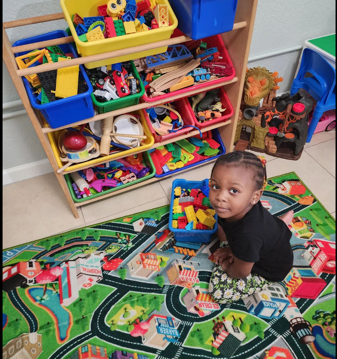 a child is sitting on a rug in front of a shelf full of toys