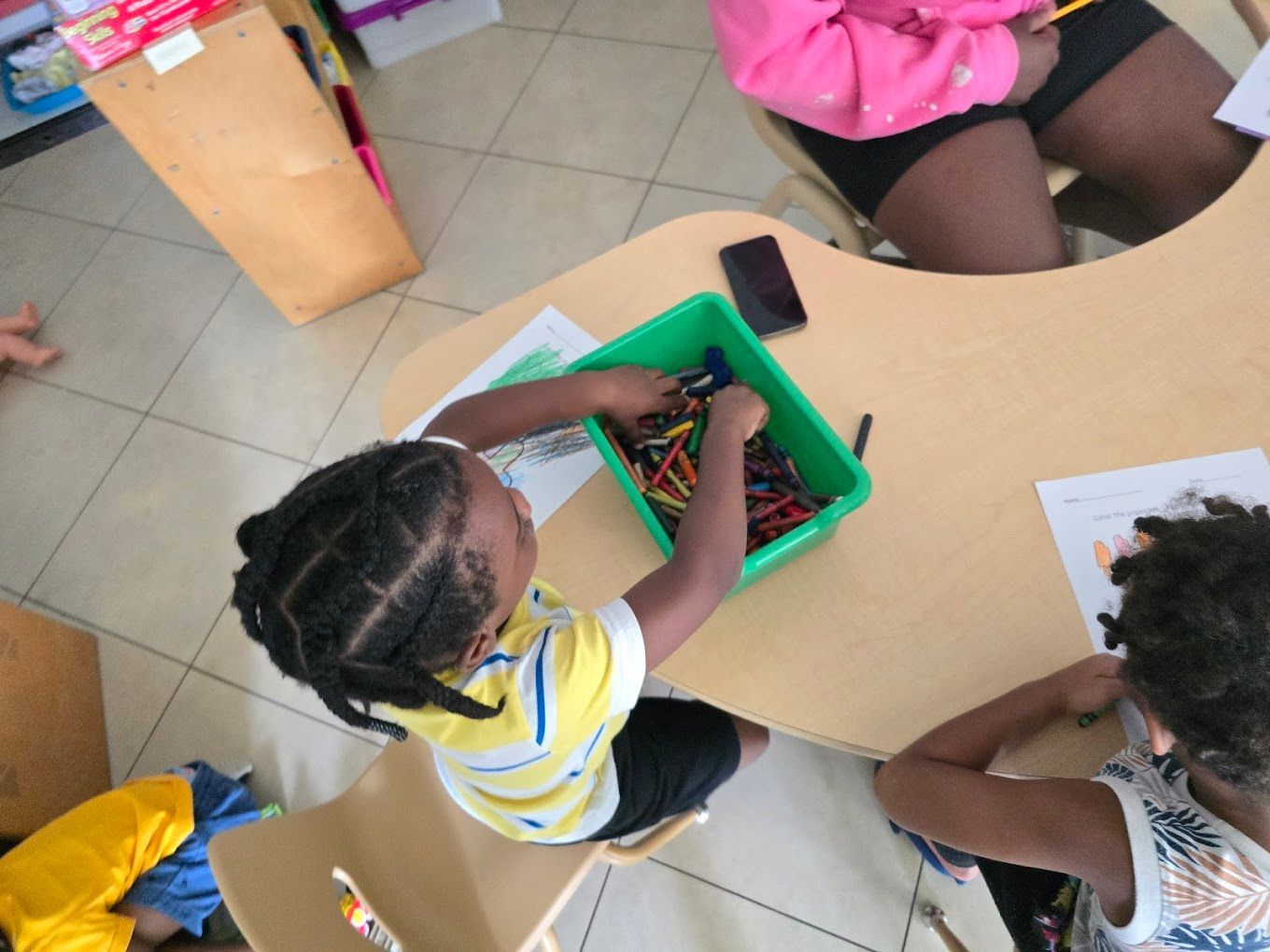 A group of children are laying in a circle on the floor