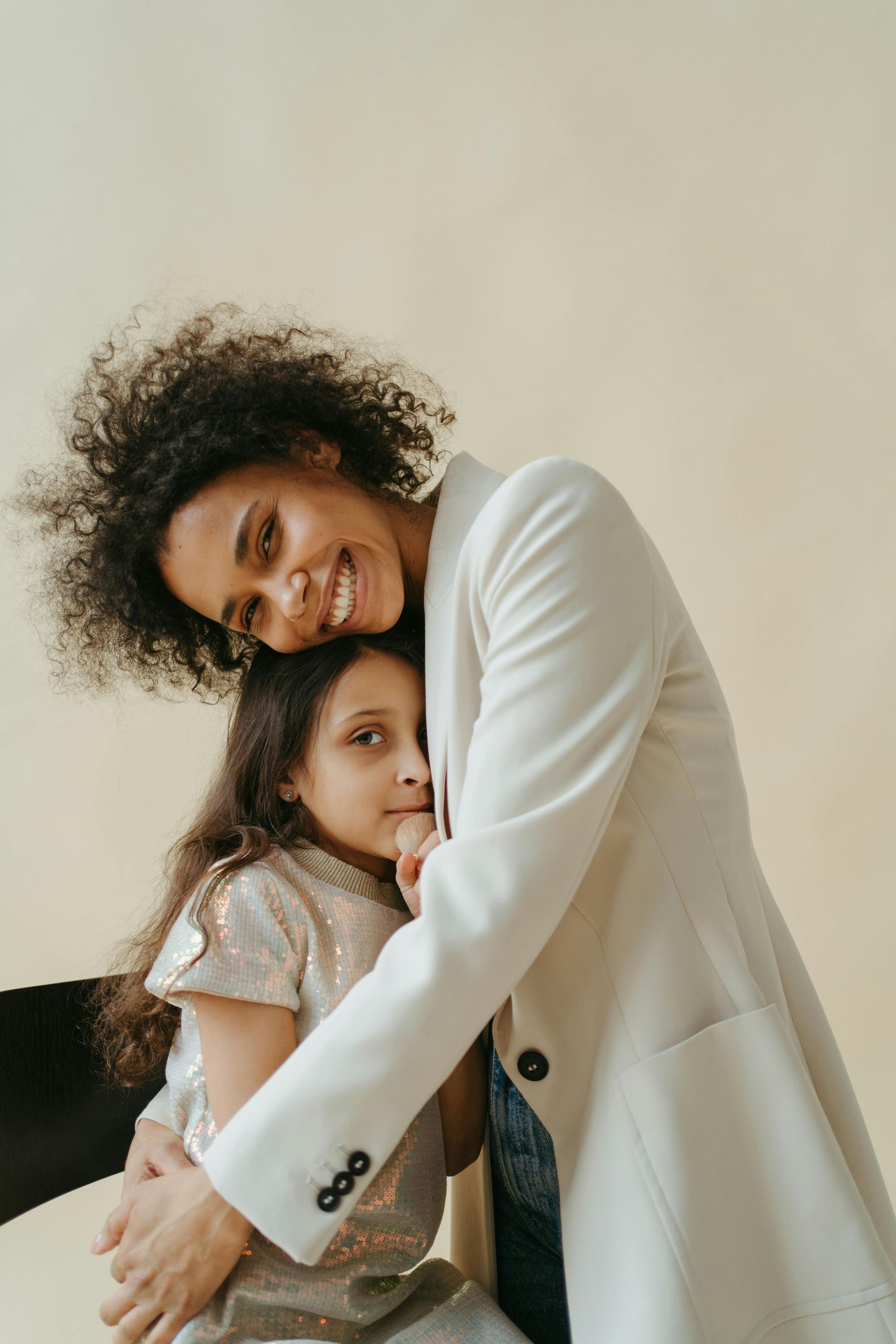 A woman in a white coat is hugging a little girl.