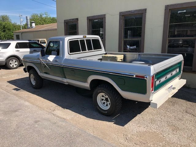 Silver and green vintage Ford pickup truck parked next to a building.