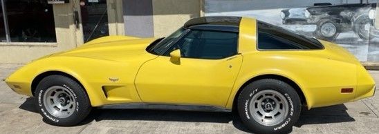 Yellow Corvette sports car with black roof parked outside.