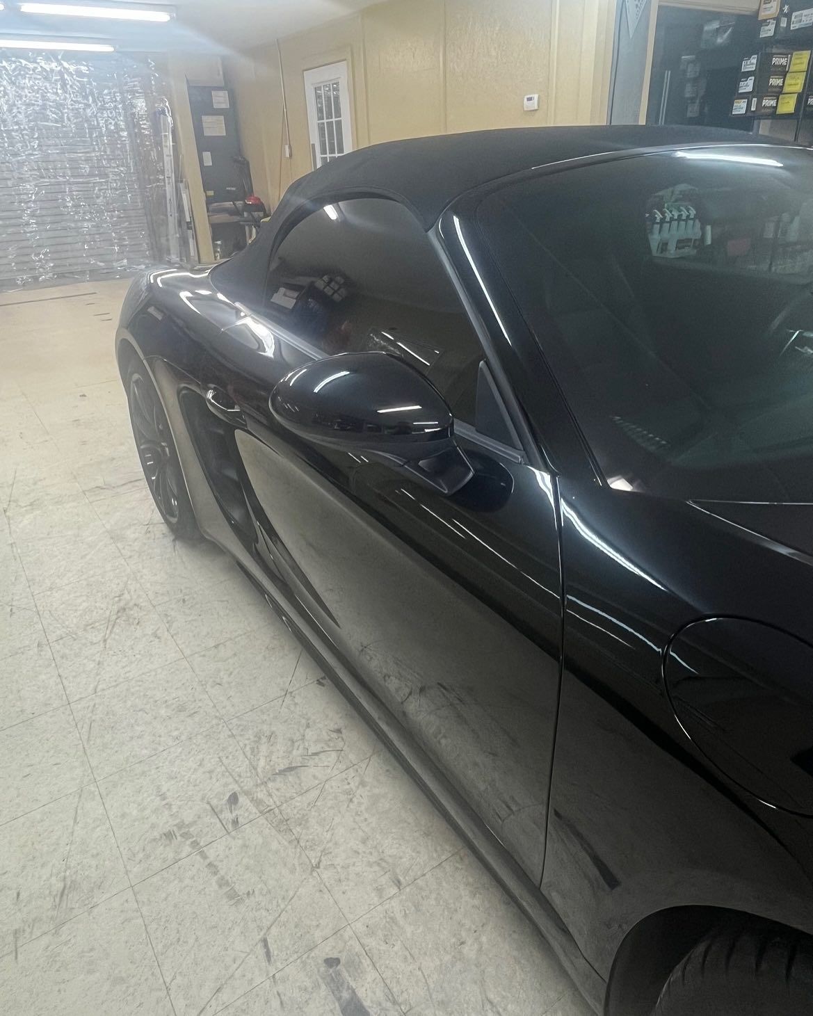 Black sports car parked indoors with tinted windows.