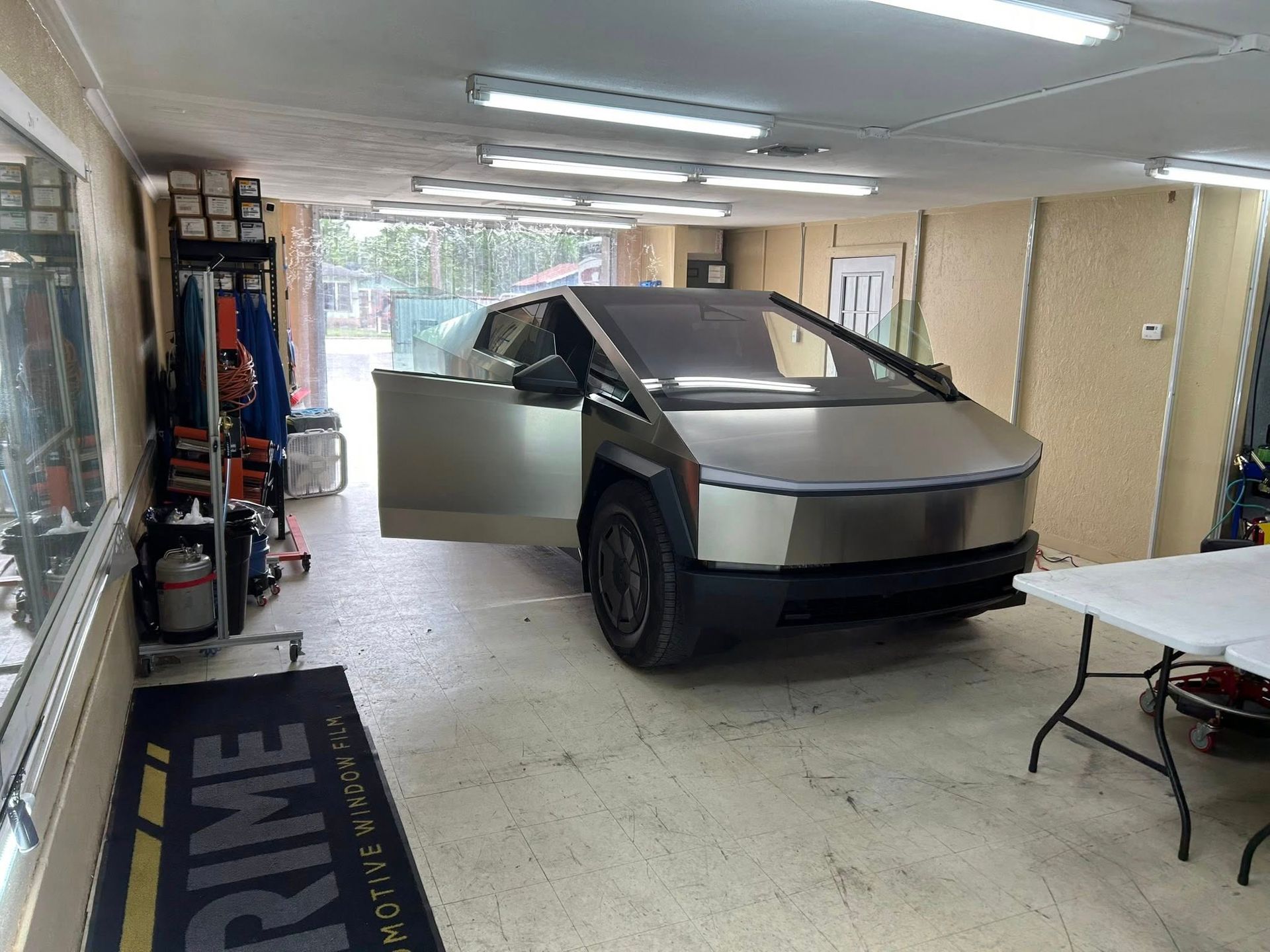 Tesla Cybertruck parked in a garage with the driver's side door open.