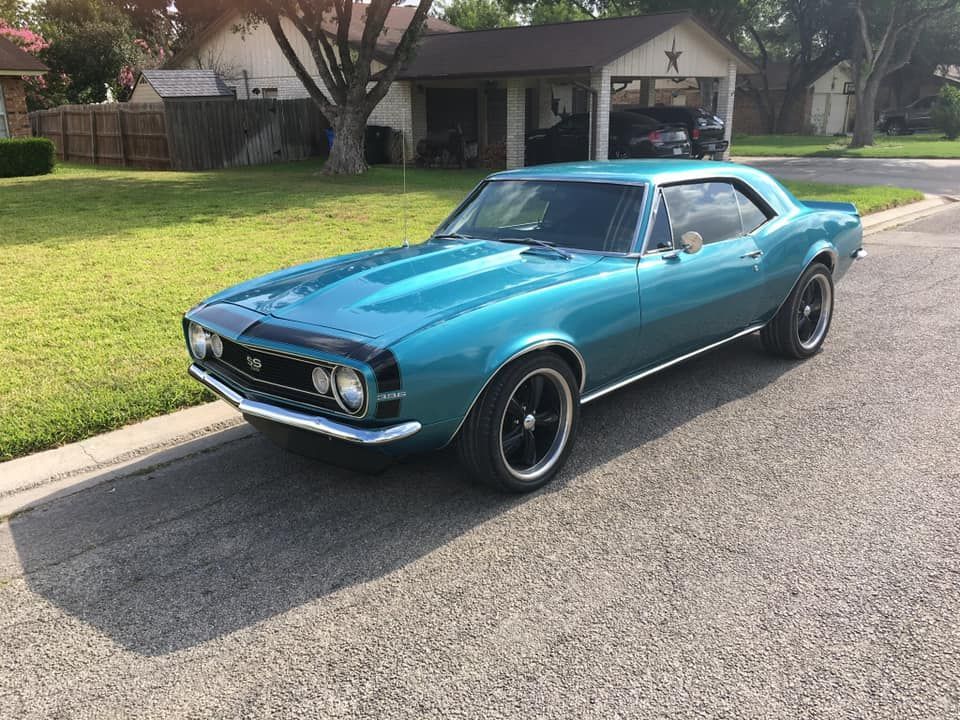 Teal 1967 Chevrolet Camaro parked on a suburban street, with black wheels and a black hood.
