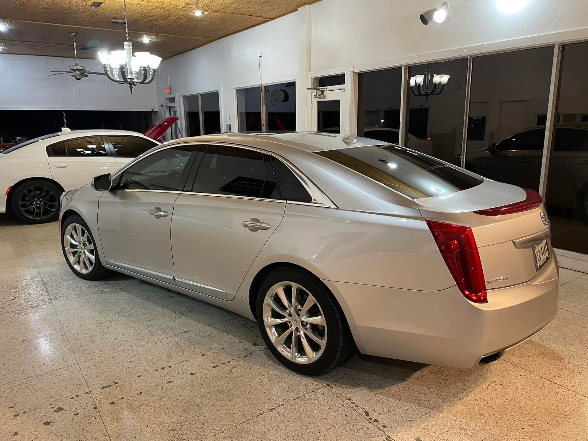 Silver Cadillac sedan in a showroom with tiled floor.