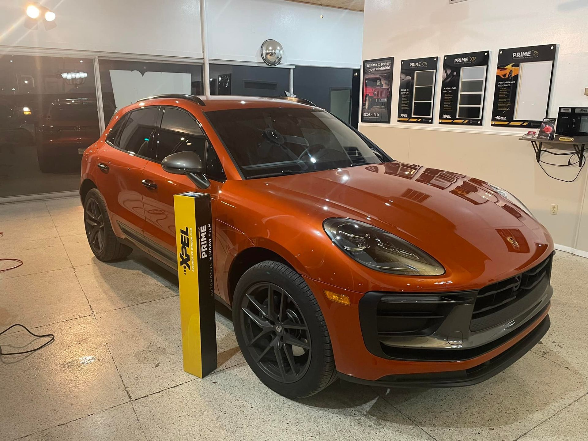 Orange Porsche Macan SUV inside a garage, with black wheels.