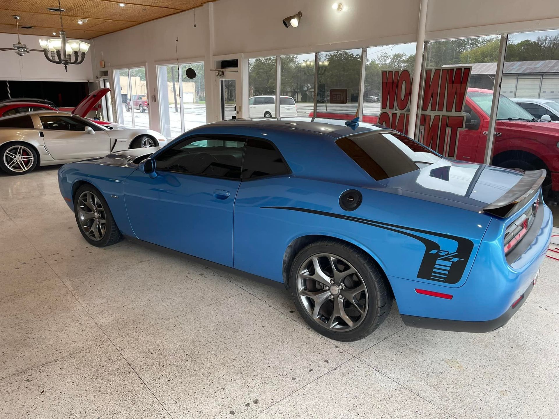 Blue Dodge Challenger in a car showroom.