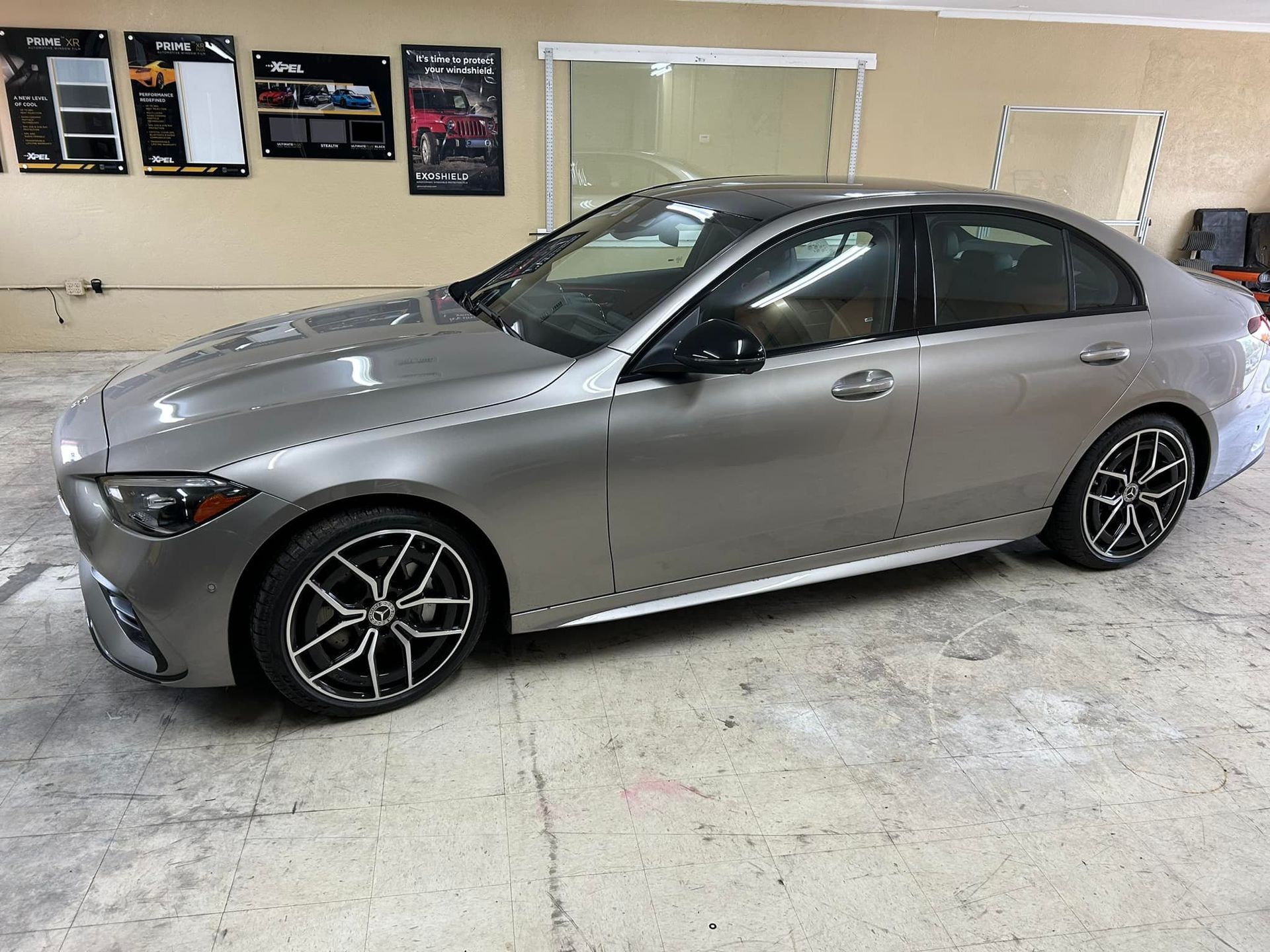 Silver Mercedes sedan with black wheels parked in a garage.