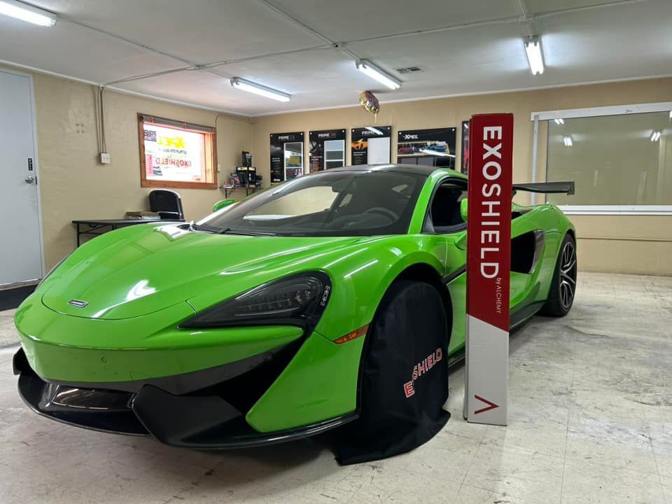 Green McLaren sports car in a garage with an Exoshield sign.