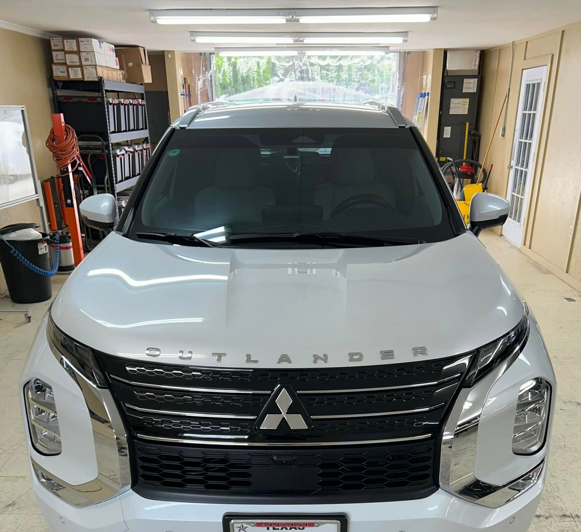 White Mitsubishi Outlander SUV parked in a garage, facing the camera.