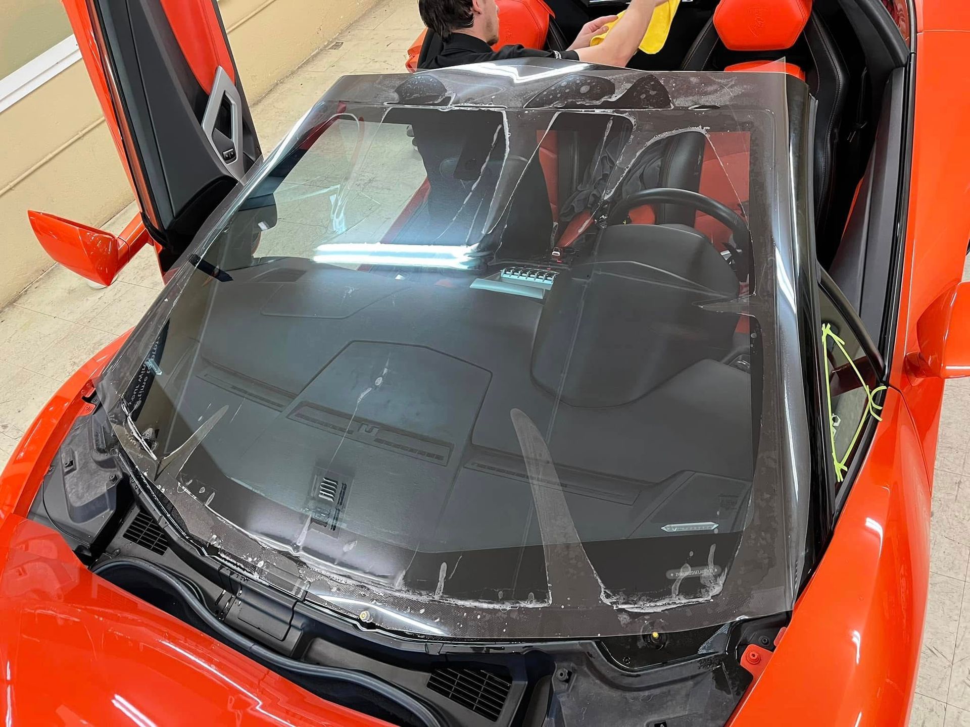 Red toy car with gullwing doors open, a child is seated inside.