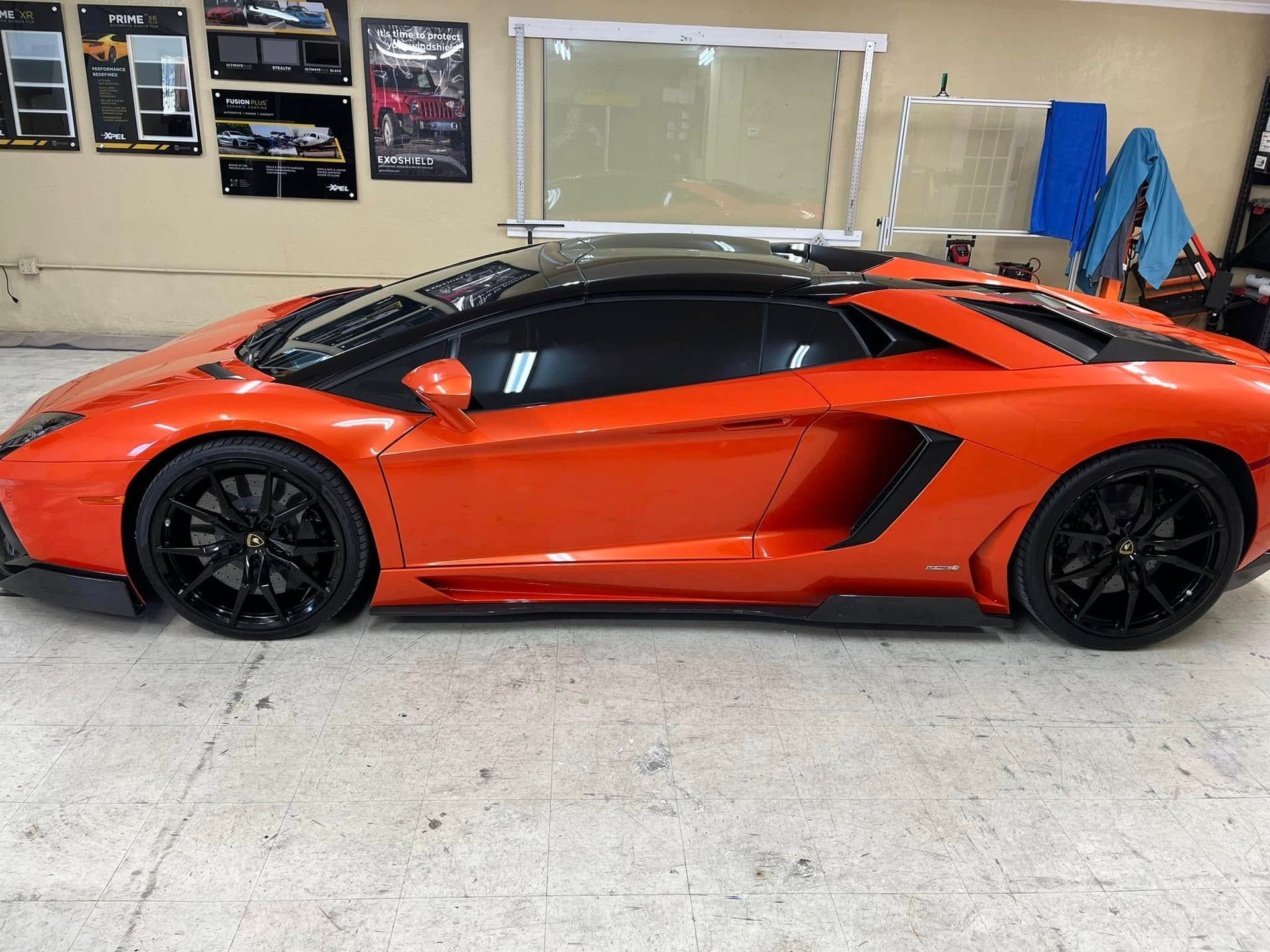 Bright orange Lamborghini with black roof and wheels in a garage.