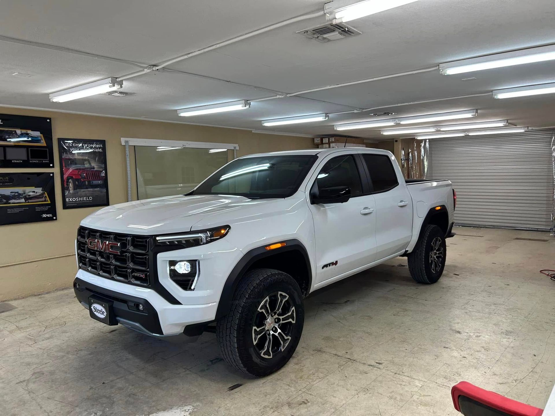 White GMC truck with black accents parked indoors, under bright lights.