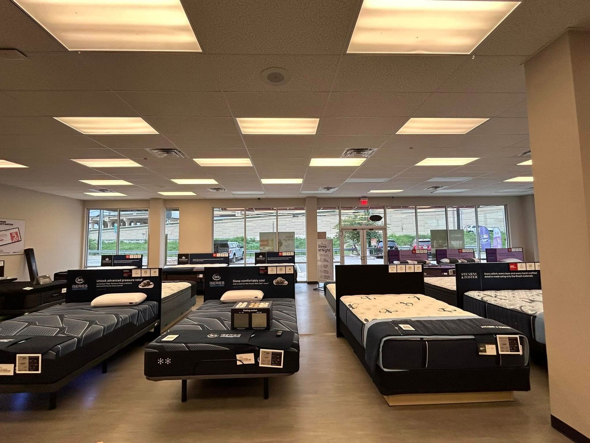 Mattress store interior with several beds on display under bright overhead lights.