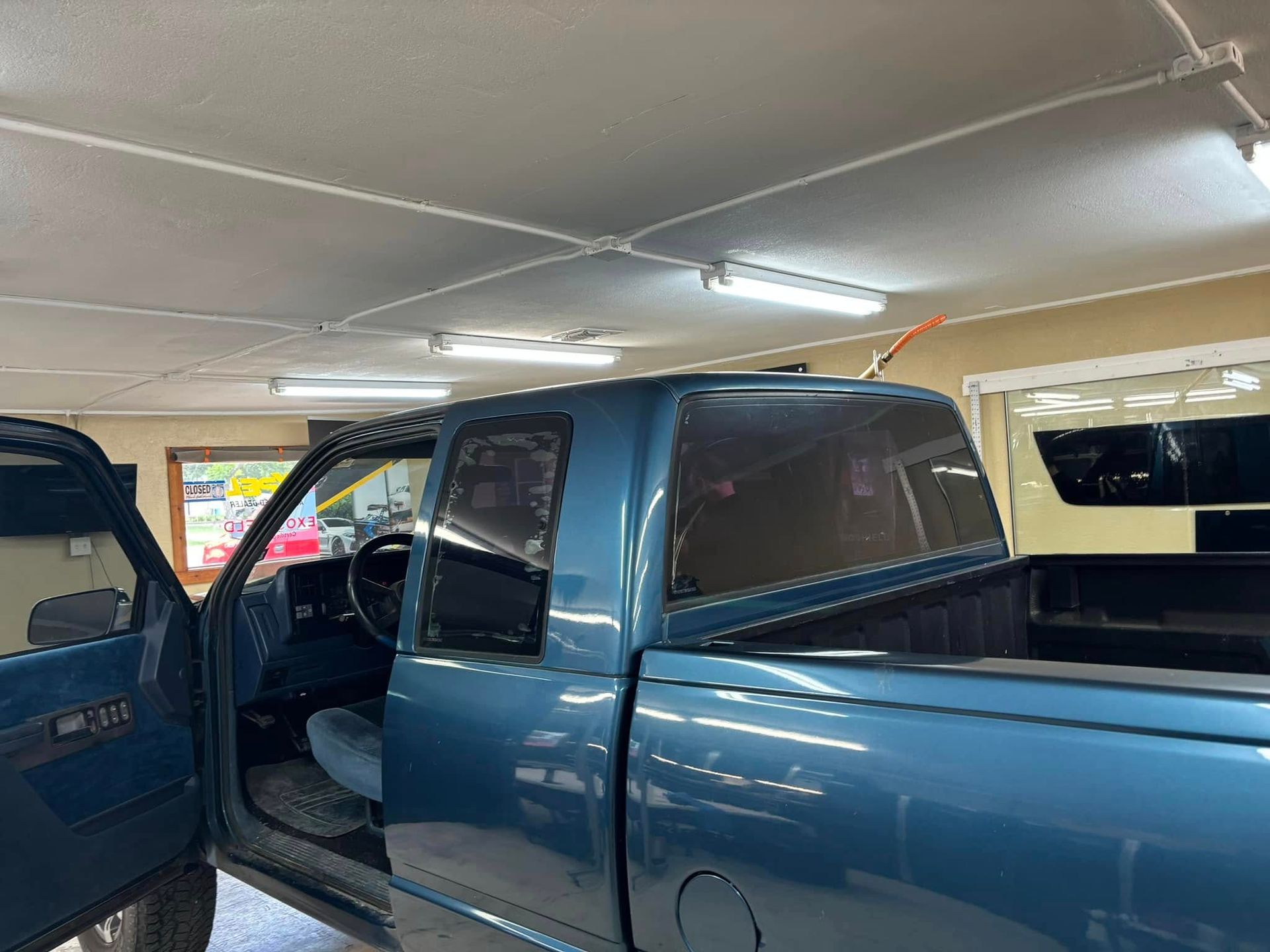 Blue pickup truck parked inside a garage with open door.