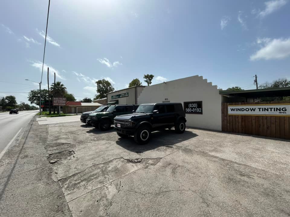 A window tinting business with three vehicles parked outside on a sunny day.