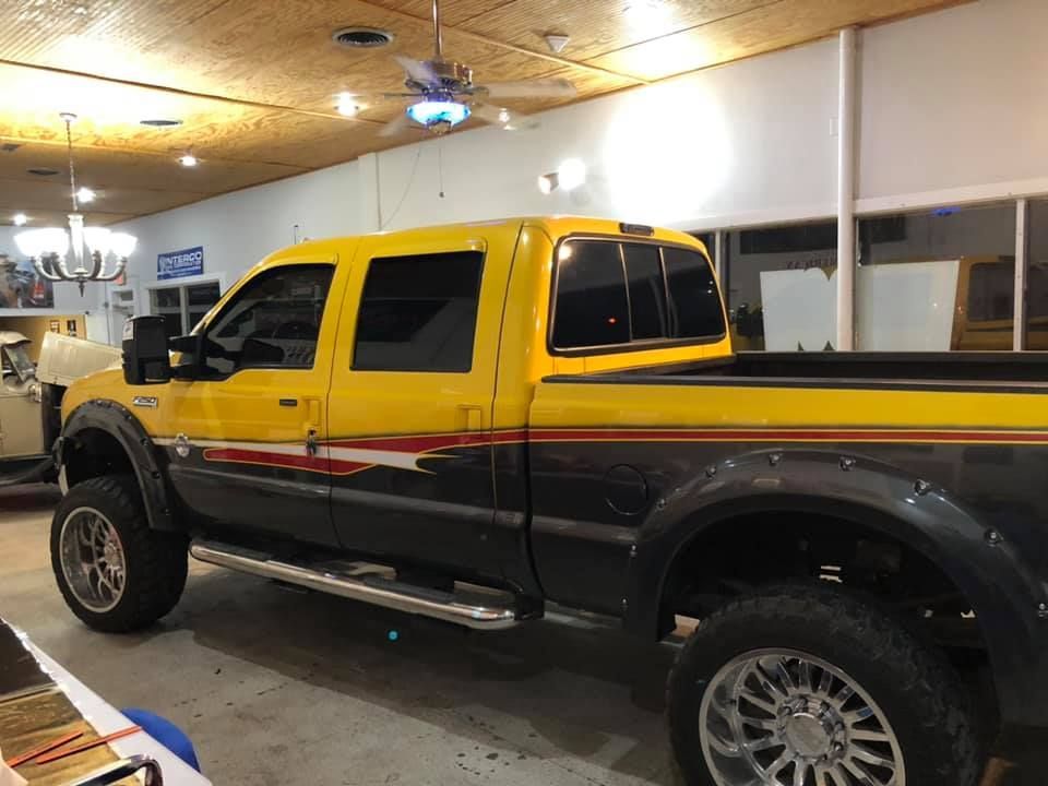 Yellow and black truck with large tires parked indoors.