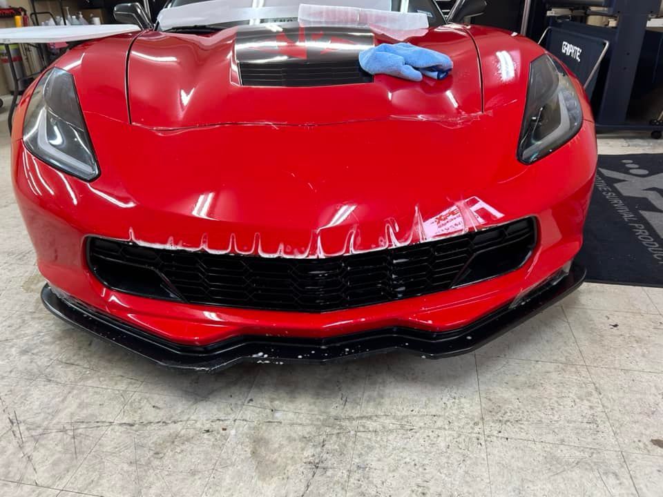 Red Corvette sports car, front view, being worked on with detail.